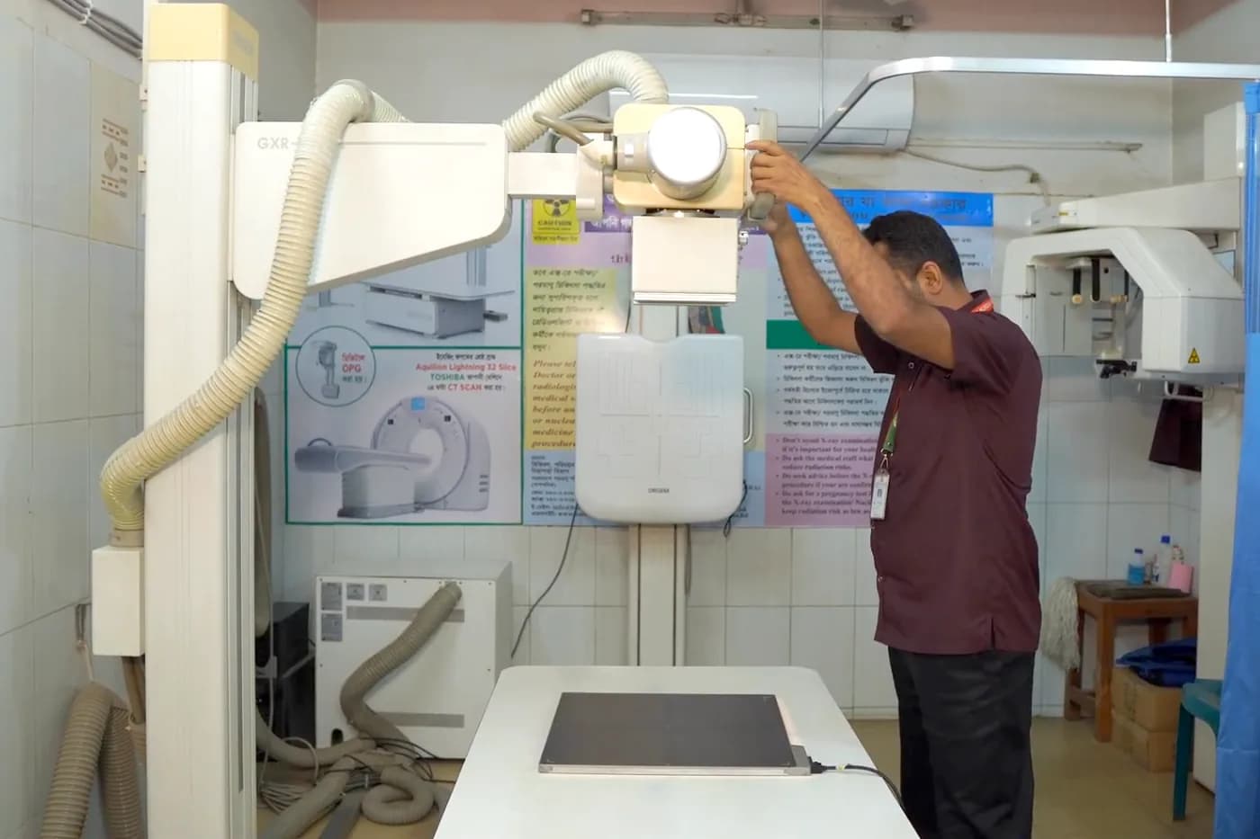 Digital X-ray machine being positioned by a technologist at Dhaka Clinic, Tangail