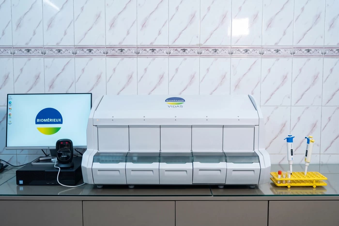 bioMérieux VIDAS immunoassay analyser at Dhaka Clinic, Tangail, with a rack of samples and pipettes beside it