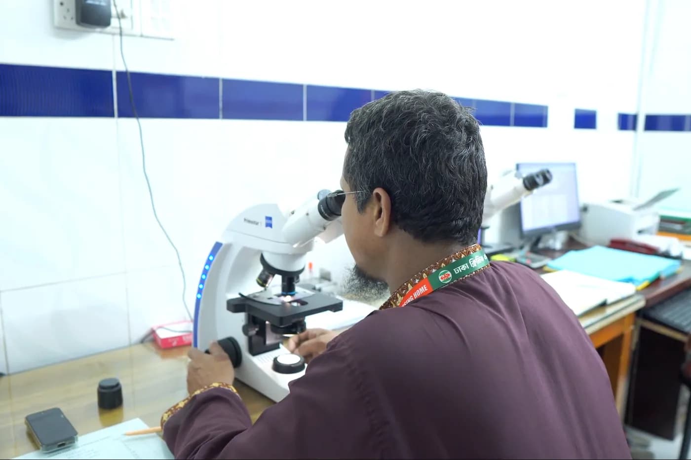 Laboratory technologist working at a microscope at Dhaka Clinic, Tangail