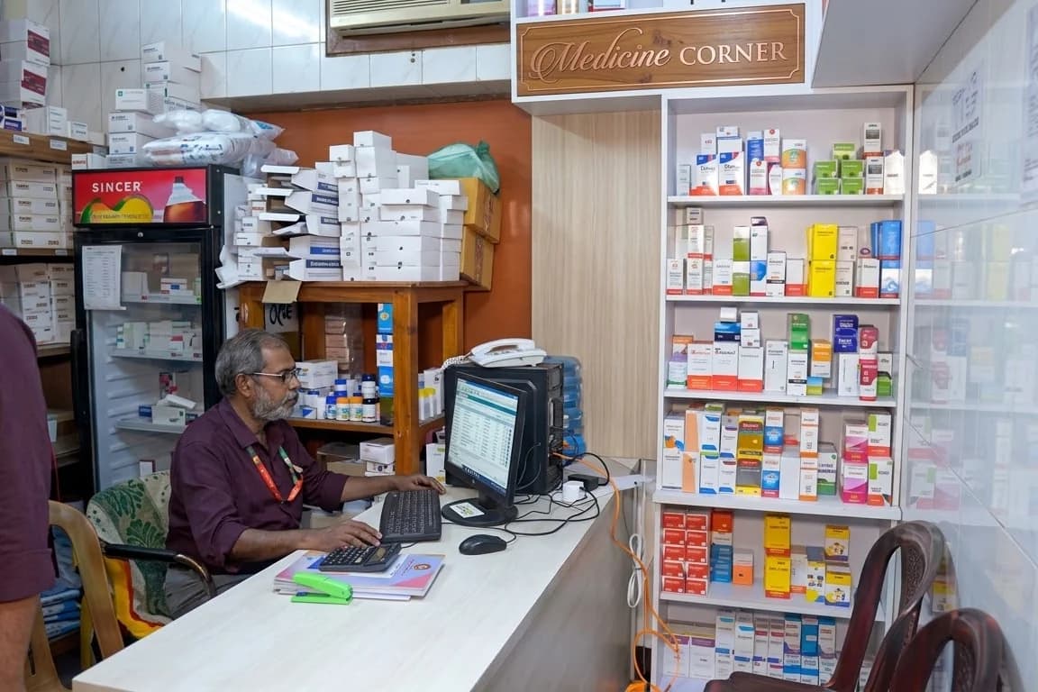 The medicine counter at Dhaka Clinic & Nursing Home, Tangail, a pharmacist at the terminal with the dispensing shelves behind
